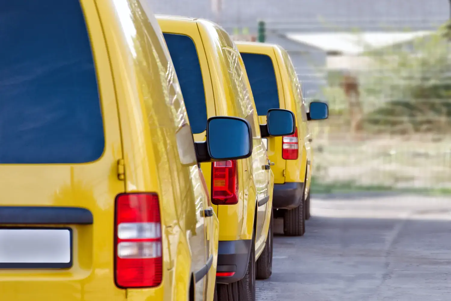 Auf dem Parkplatz stehen gelbe Kurier- oder Taxiwagen.